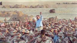 President George H. W. Bush and first lady Barbara Bush wave goodbye to U.S. Marines and members of the British 7th Armoured Brigade as they conclude a Thanksgiving Day visit with troops in the Saudi desert in this November 22, 1990 file photo.