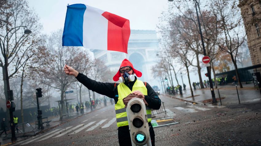 A demonstrator holds a French flag near the Arc de Triomphe during a demonstration Saturday, Dec.1, 2018 in Paris. Paris police say at least 63 people have been arrested in violent clashes between protesters and police amid nationwide demonstrations against rising taxes and President Emmanuel Macron's policies. (AP Photo/Kamil Zihnioglu)