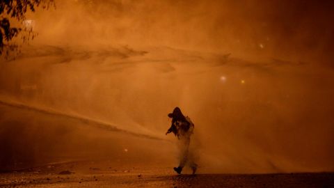 A demonstrator leaves as water cannons evacuate the Place de l'Etoile on  Saturday, December 1, in Paris.
