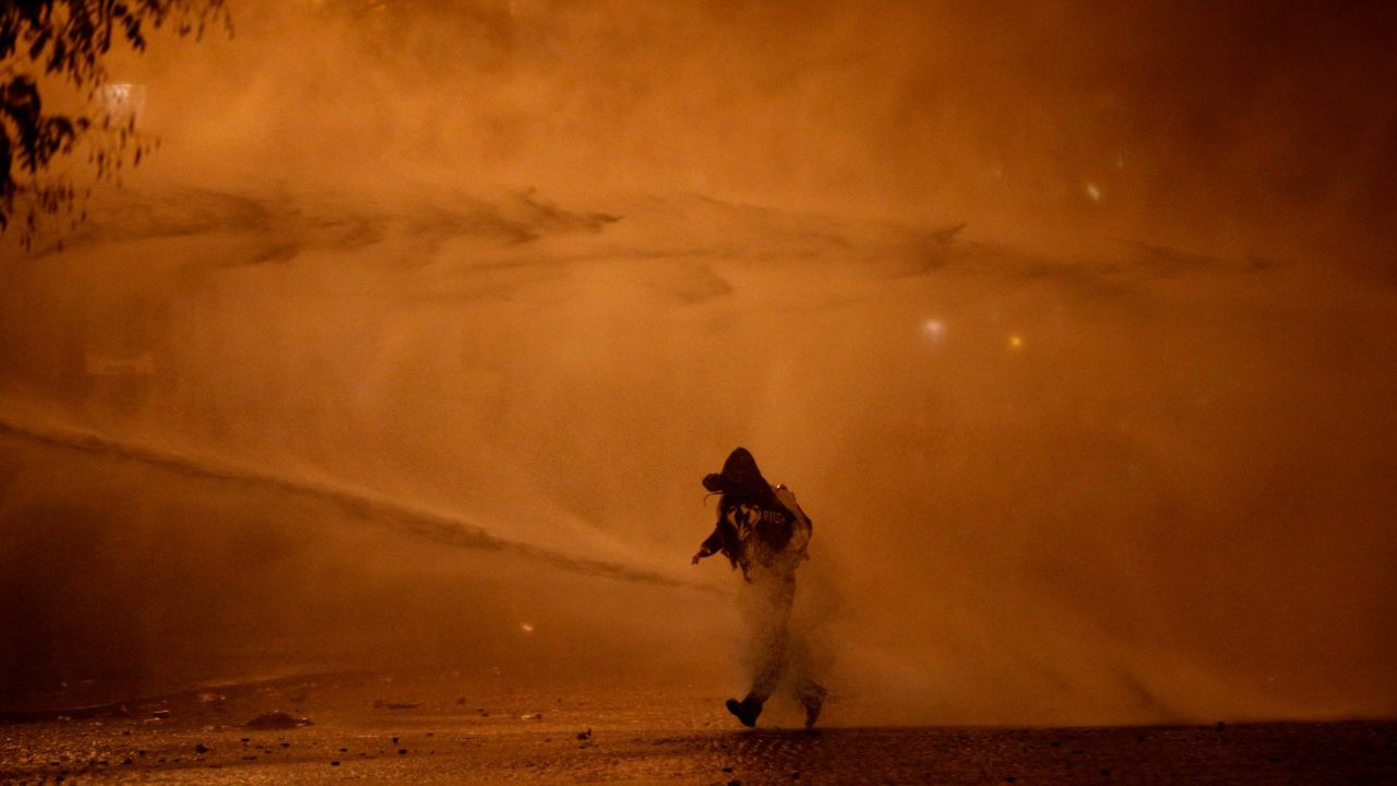 A demonstrator leaves as water cannons evacuate the Place de l'Etoile on Saturday, December 1, in Paris.