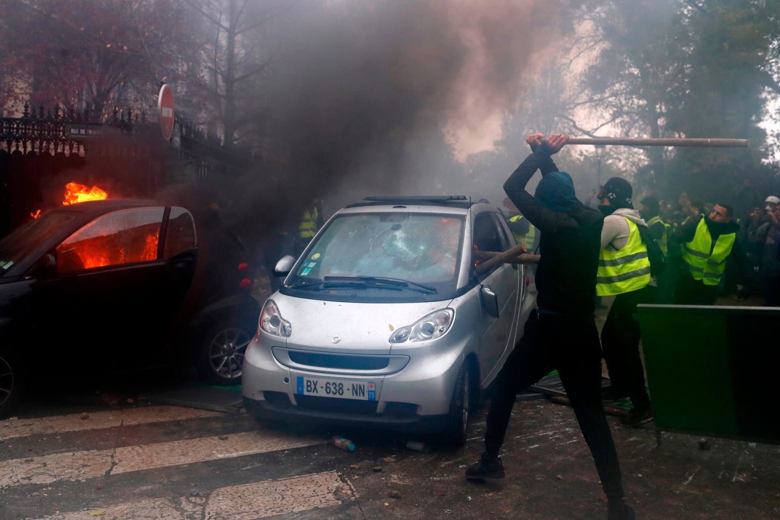 Hooded demonstrators smash a car.