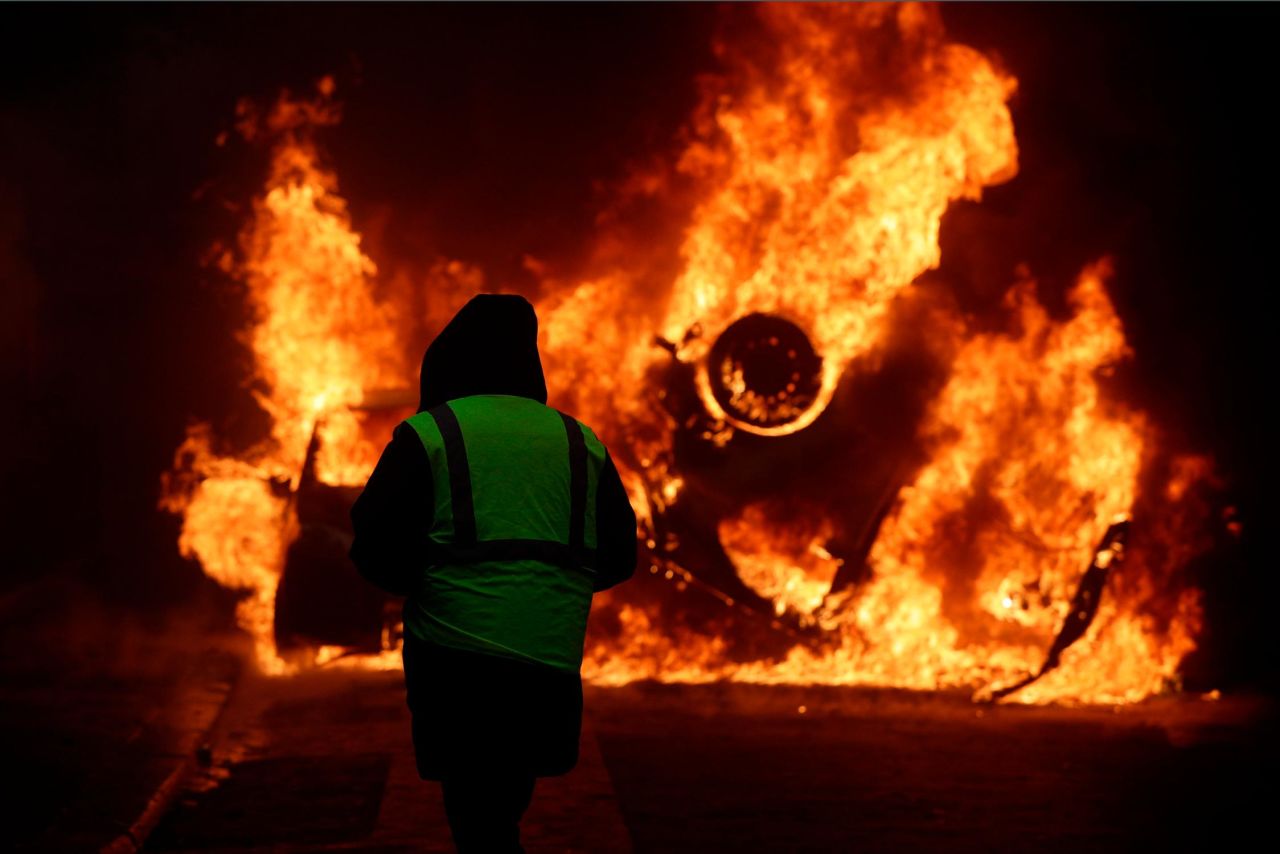 A demonstrator watches a burning car near the Champs-Elysees avenue on December 1.