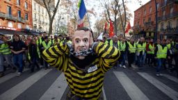 A false Macron shut his ears as people shout 'Macron, demission'. Protesters called 'Gilets jaunes' (ie Yellow vests) protest against the rise of taxes on oil products. They organized themselves by social networks to block roads, accesses to airports, etc. Mostly said that the rise of taxes on oil products was the detonator of their wrath
