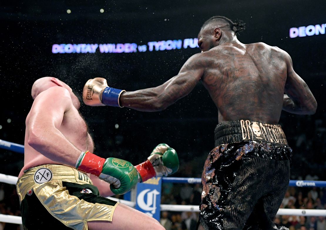 Deontay Wilder knocks Tyson Fury down during the 12th round to earn the draw and retain his belt. 