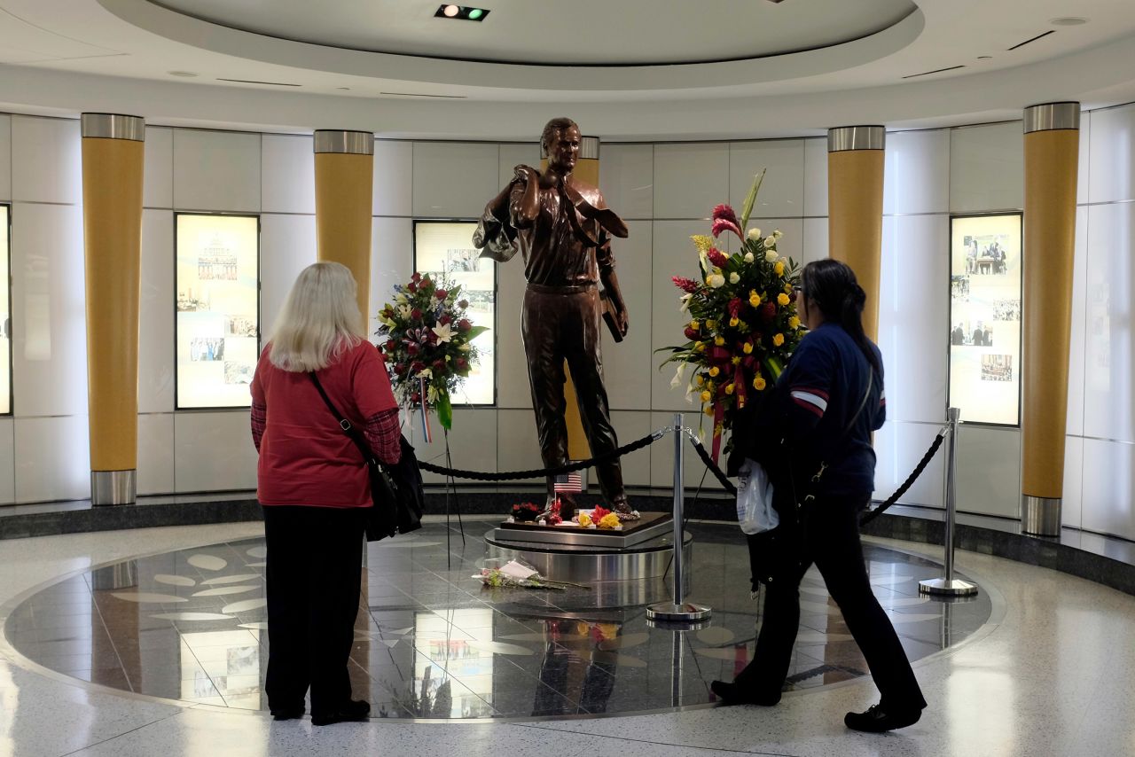 Travelers stop at a statue of the former President as they arrive at Houston's George Bush Intercontinental Airport on Sunday, December 2.