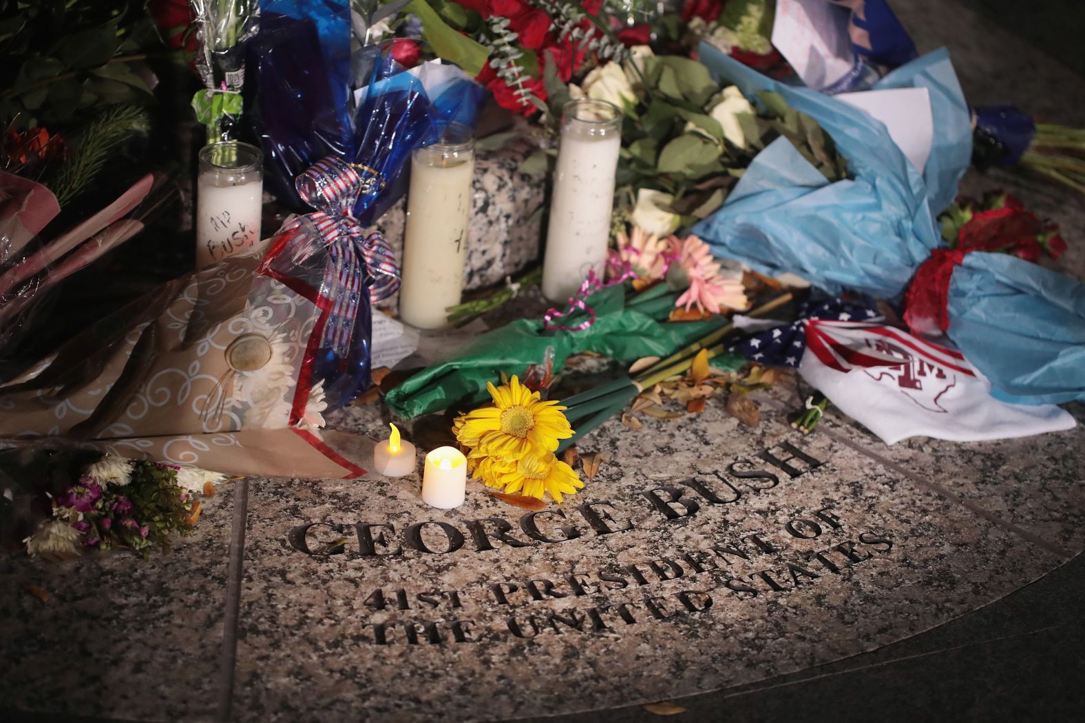 Flowers are left at the base of a Bush statue on the campus of Texas A&M.