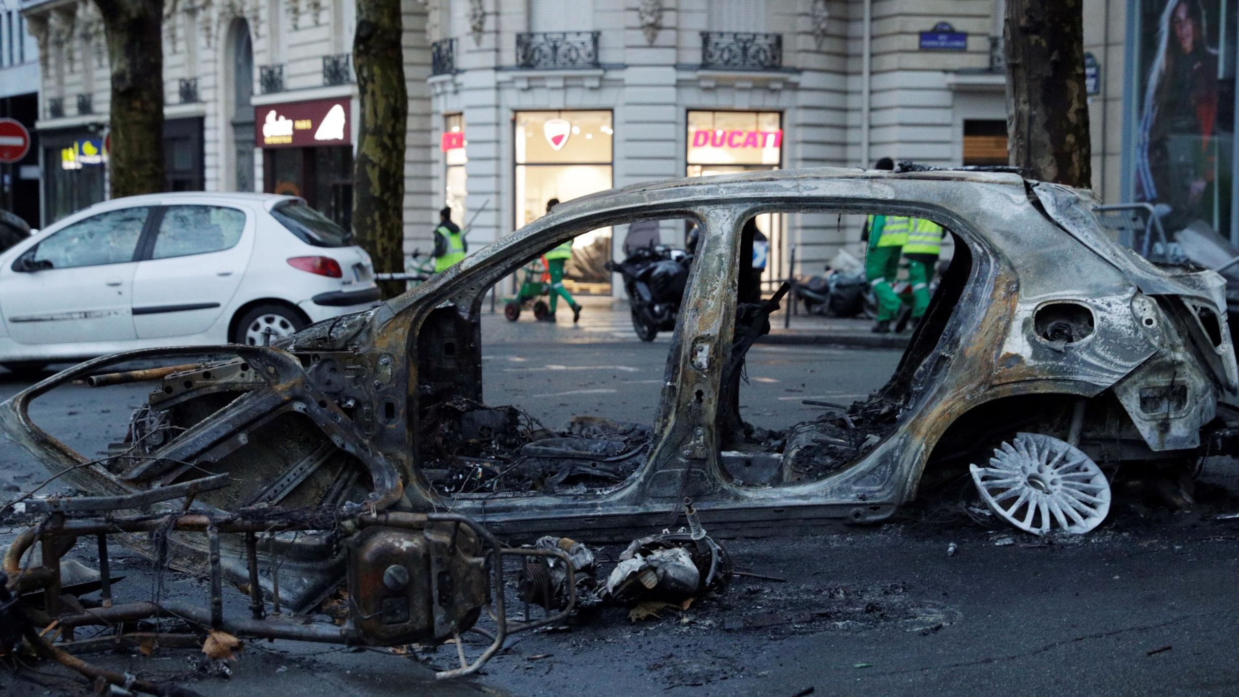 A burned-out car sits in a Paris street the day after riots spread through the city.