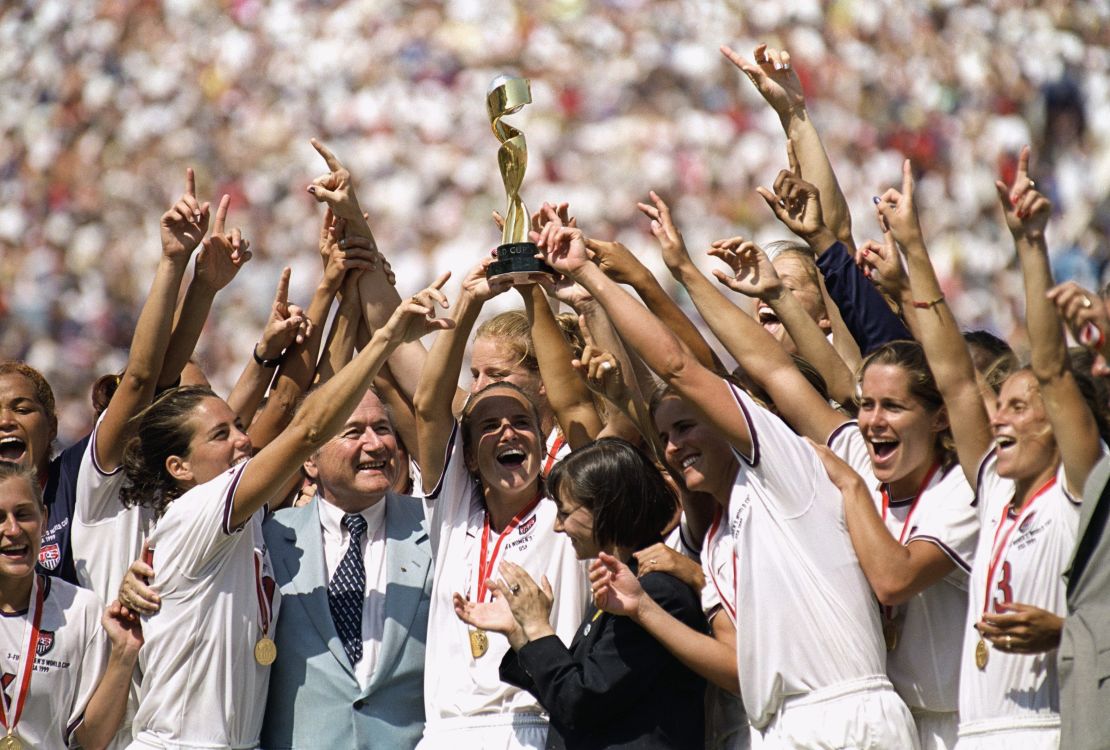 PASADENA, CALIFORNIA - JULY 10:  Captian Carla Overbeck #4 of the US Women's Soccer Team raises the World Cup Trophy, as the team celebrates their victory over Team China in the Championship match of the FIFA Women's World Cup at the Rose Bowl on July 10, 1999 in Pasadena, California.  Team USA defeated Team China 5-4 in sudden death after two overtimes.  (Photo by Harry How/Getty Images)