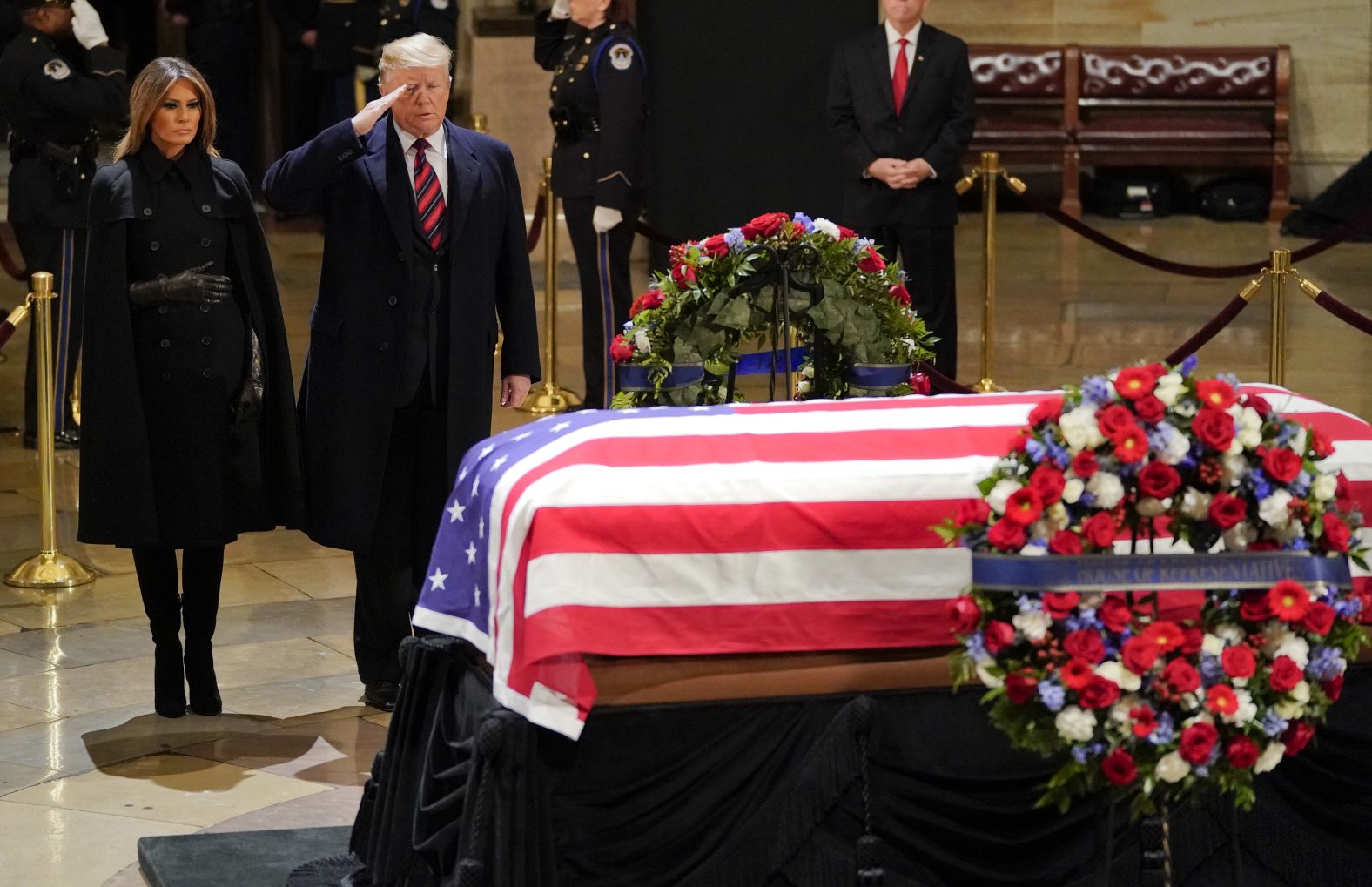 President Donald Trump salutes as he and first lady Melania Trump pay their respects to Bush on December 3. 