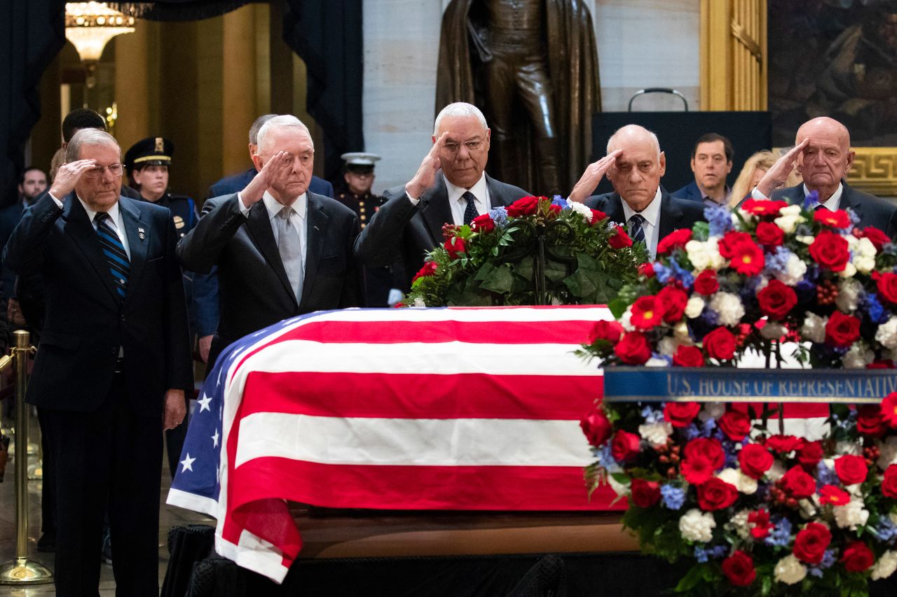 Former Secretary of State Colin Powell, who under Bush was chairman of the Joint Chiefs of Staff, salutes Bush at center along with other former military officials.