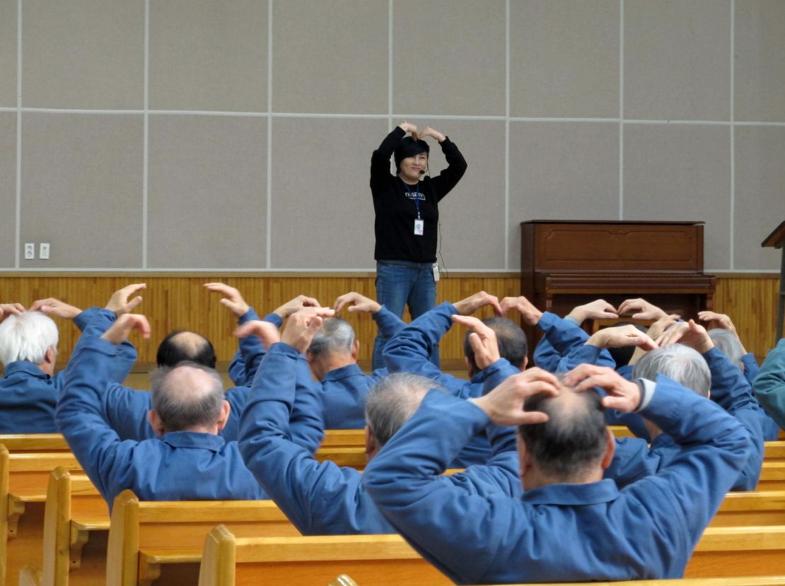 An aerobics instructor leads elderly inmates in simple exercises. 