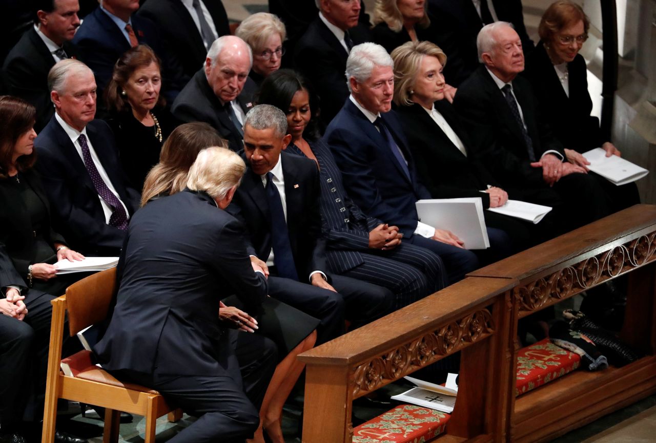 President Donald Trump reaches over to shake hands with former President Barack Obama as he and his wife, Melania, take a seat in the first row along with former first lady Michelle Obama, former President Bill Clinton, former first lady Hillary Clinton, former President Jimmy Carter and former first lady Rosalynn Carter.