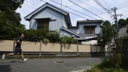 A man runs past a vacant house in the Yato area of Yokosuka City, Kanagawa Prefecture, Japan, on Wednesday, Aug. 21, 2013. More than 50 houses and apartments, almost 20 percent of the quaint residential neighborhood of narrow streets and stairway paths leading into green hills, are empty here, an hour's train ride south of Tokyo and 1,000 yards (900 meters) from the Yokosuka naval base, home of the U.S. Seventh Fleet. Photographer: Akio Kon/Bloomberg via Getty Images