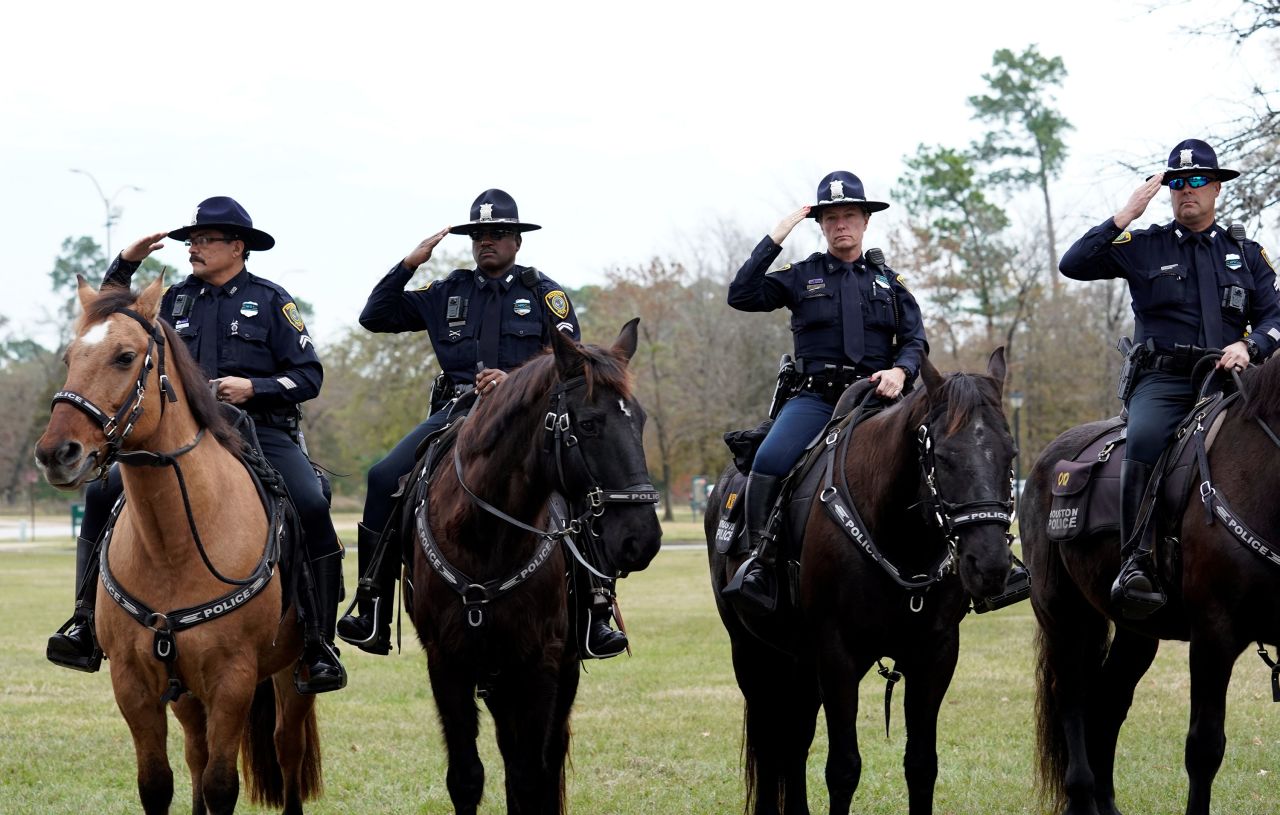 Police salute as a hearse carries Bush's casket to a train facility in Houston on December 6.