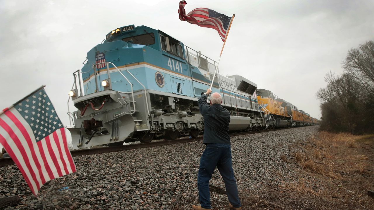 Peter Olyniec waves an American flag as George H.W. Bush's train passes near Whitehall, Texas, on Thursday, December 6. Bush's body was en route to his presidential library in College Station, Texas, where he was laid to rest.