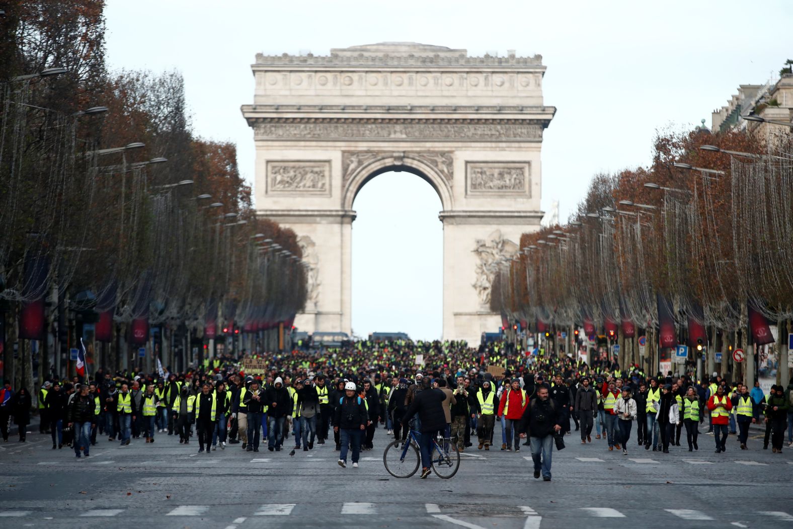 Protesters wearing yellow vests walk on the Champs-Elysees Avenue with the Arc de Triomphe in the background during a protest on December 8.