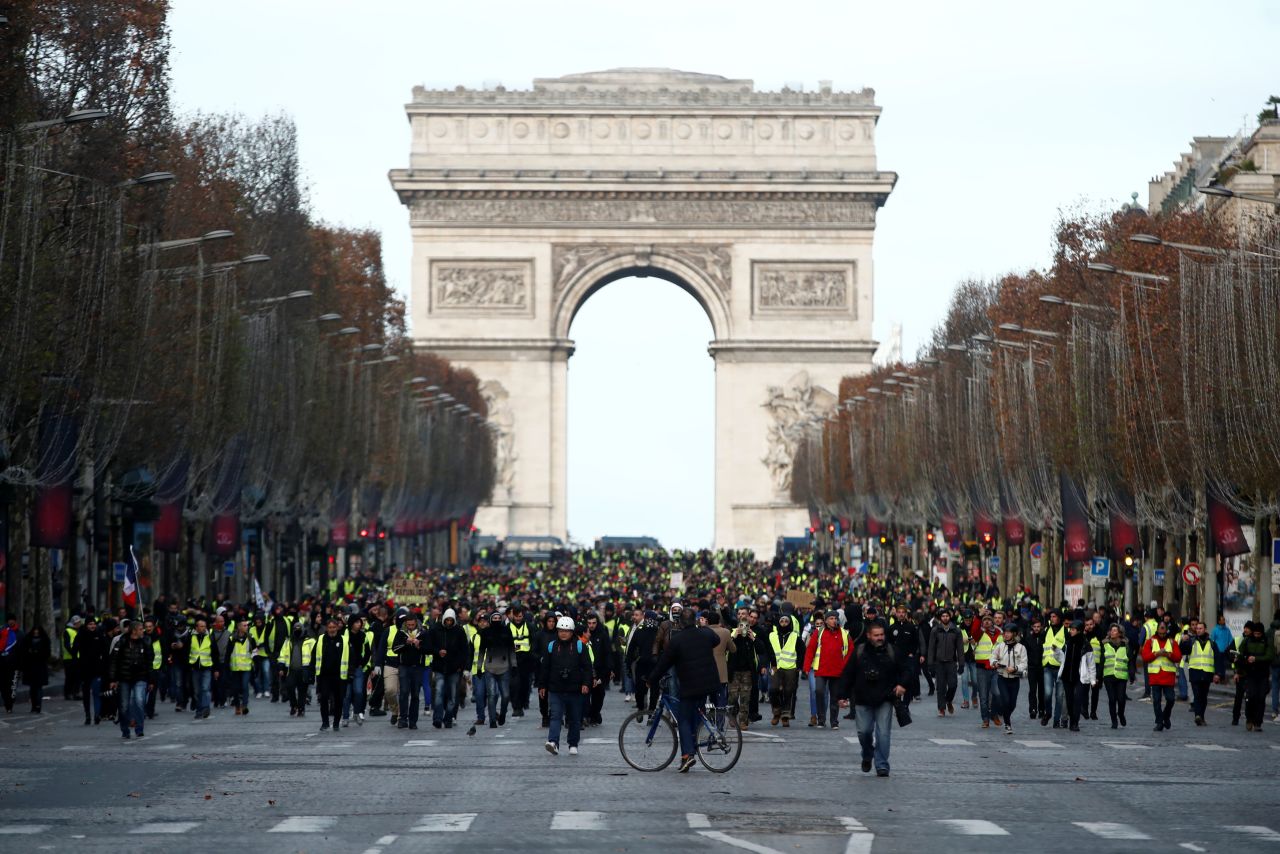 Protesters wearing yellow vests walk on the Champs-Elysees Avenue with the Arc de Triomphe in the background during a protest on December 8.