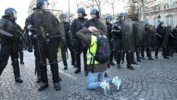 A protestor wearing a "yellow vest" (gilet jaune) kneels  in front of the police forces on the Champs Elysees avenue in Paris on December 8, 2018 during a protest against rising costs of living they blame on high taxes. - Paris was on high alert on December 8 with major security measures in place ahead of fresh "yellow vest" protests which authorities fear could turn violent for a second weekend in a row. (Photo by Zakaria ABDELKAFI / AFP)        (Photo credit should read ZAKARIA ABDELKAFI/AFP/Getty Images)