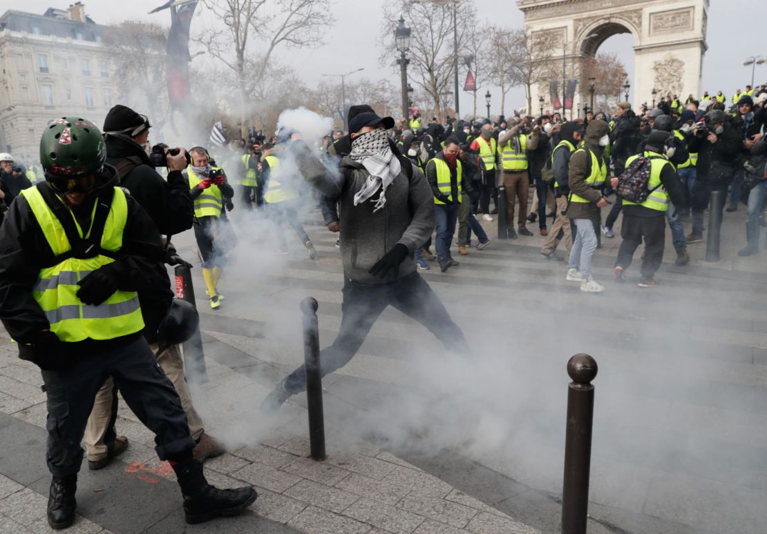 Yellow vest protesters clash with riot police near the Arc de Triomphe, where weeks earlier, Macron addressed world leaders.