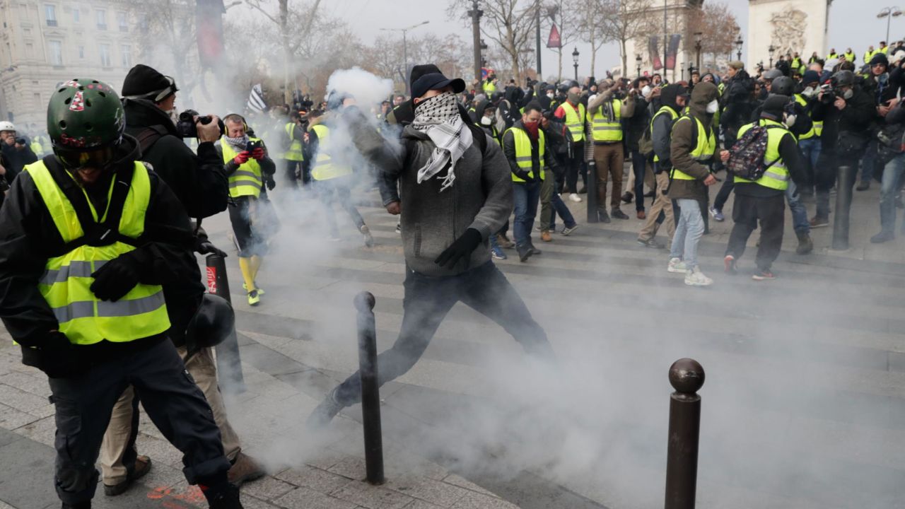 Yellow vest protesters clash with riot police near the Arc de Triomphe, where weeks earlier, Macron addressed world leaders.