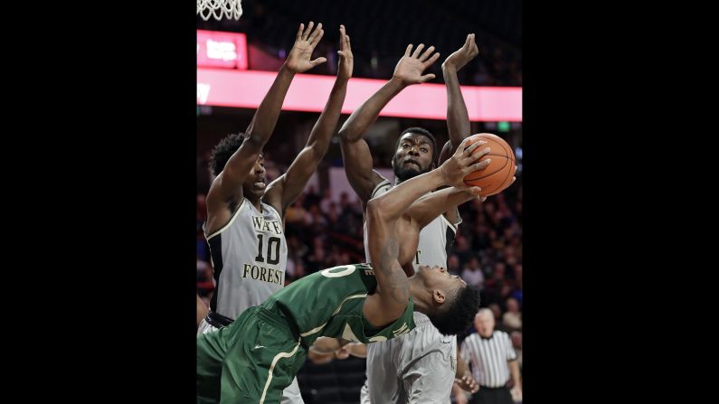 Charlotte's Dravon Mangum falls as he tries to shoot over Wake Forest's Jaylen Hoard and Ikenna Smart in the second half of an NCAA basketball game in Winston-Salem, North Carolina, Thursday, December 6.