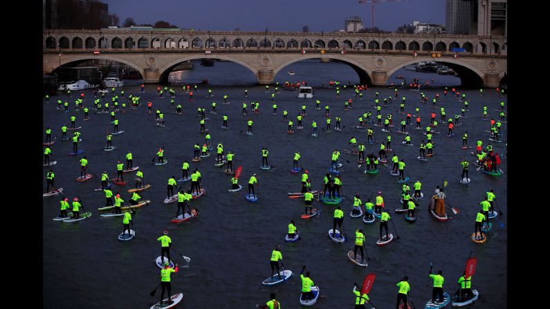 Participants paddle along the Seine river in the Nautic SUP Paris Crossing, a stand up paddle competition in Paris, France on Sunday, December 9.