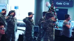 Travelers at Nashville International Airport stand at attention as "The Star Spangled Banner" is sung on Saturday for children of fallen service members