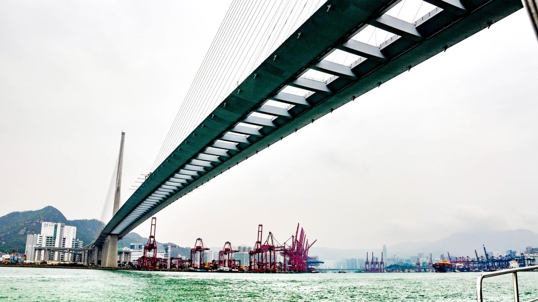 <strong>Sea scenes: </strong>The cranes of Hong Kong's container port loom in the background as a tour boat to Tsing Yi island approaches under the bridge. 