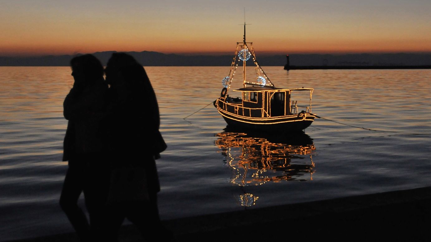 <strong>Greece:</strong> People walk past a traditional Christmas boat decorated with colorful lights docked in the Thermaic Gulf off the shores of Thessaloniki. Greeks are increasingly turning to decorating small Christmas boats instead of trees.