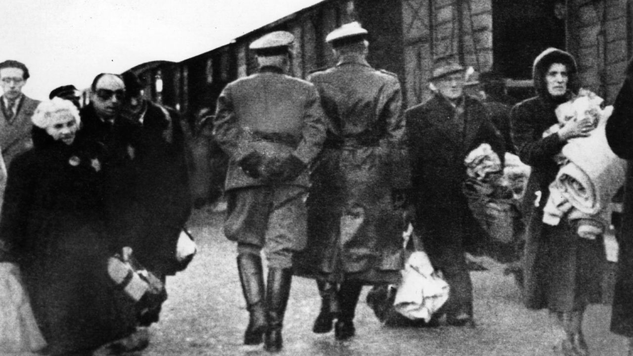 Nazi officers supervise Jews leaving railway trucks during the deportation to the camps in 1941.