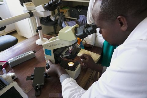 A lab technician at Kiruddu General Hospital examines a microscope slide for malaria. 