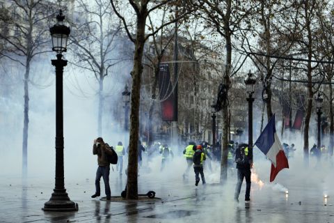 Demonstrators run through tear gas during scuffles with police December 15 on the Champs-Élysées in Paris.
