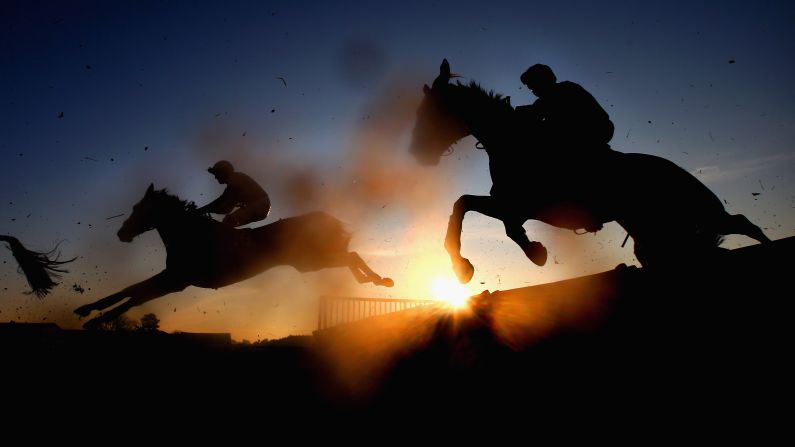 Horseback riders jump a fence during the Cliftons of Wrexham Novices' Hurdle Race in Bangor, Wales on Friday, December 14.