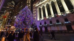 People walk past a Christmas tree at the New York Stock Exchange on November 30, 2018 in New York City. - Wall Street finished a banner week on a positive note, borne higher by optimism about US-China trade talks while Microsoft overtook Apple in market value. Major US indices all finished the session solidly higher to cap a strong week. The S