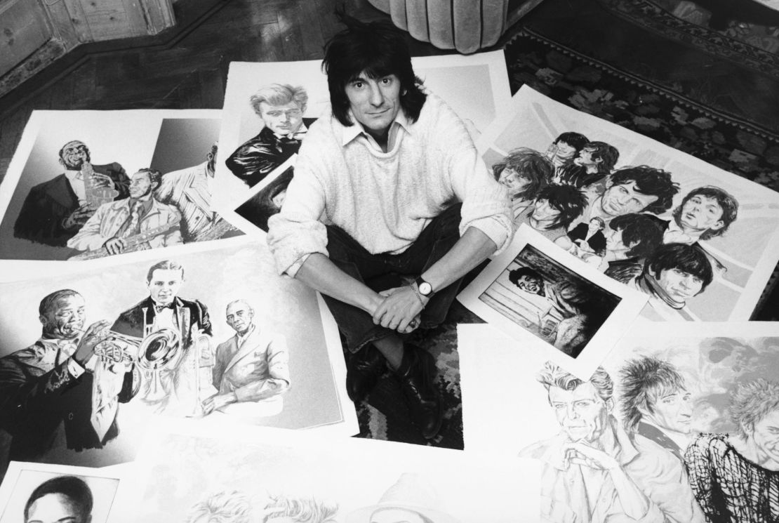 Rolling Stones guitarist Ronnie Wood poses with his drawings of fellow musicians in 1987.
