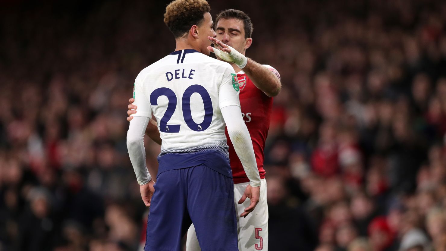 Deli Alli looks towards the fans after being hit by a water bottle. 