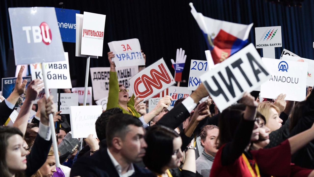 Journalists at Russian President Vladimir Putin's annual end-of-year news conference hold up signs to attract his attention.