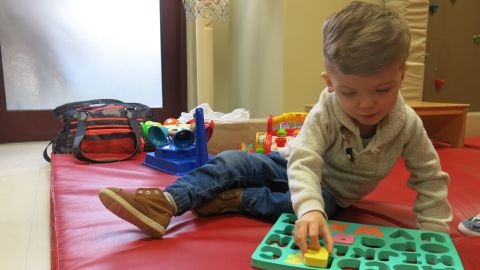 Jadon plays with letters of the alphabet during a physical therapy session.