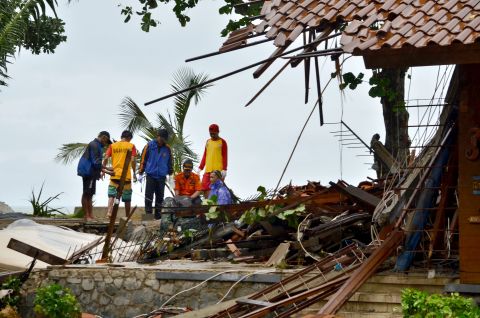 Officials look through the wreckage of damaged buildings in Carita, Indonesia.