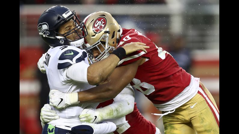Seattle Seahawks quarterback Russell Wilson is hit by San Francisco 49ers linebackers Fred Warner and Elijah Lee during the second half of their football game in Santa Clara, California on Sunday, December 16.