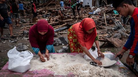 Women collect rice from their destroyed houses in Carita.