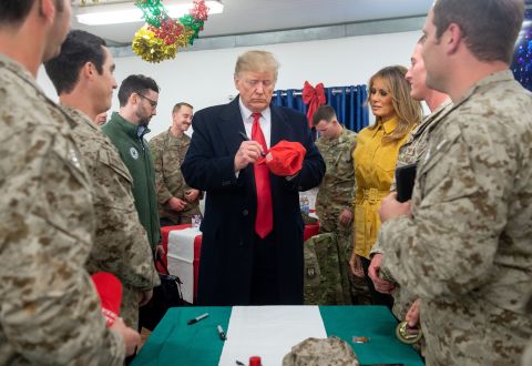 President Trump signs "Make America Great Again" hats for US troops during his surprise visit.