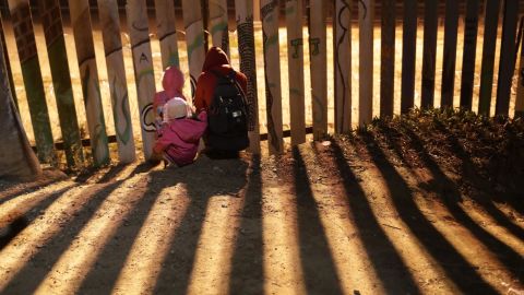 Immigrants wait to climb over the US-Mexico border fence on December 2, 2018, in Tijuana, Mexico.