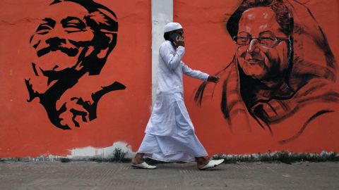 A man walks past a wall with images of Bangladeshi founding father Sheikh Mujibur Rahman and Prime Minister Sheikh Hasina Wazed in Dhaka, Bangladesh. 