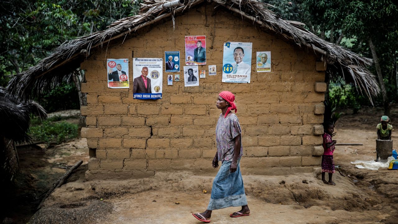 A woman walks in front of electoral posters in the remote village of Bonde, Kongo Central province, on December 26.