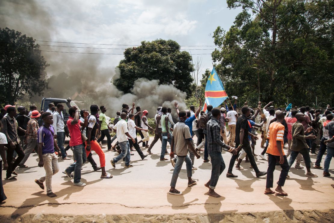 Protesters march in front of a police platoon near the electoral commission in Beni on December 27.
