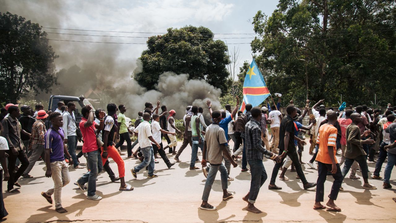 Protesters march in front of a police platoon near the electoral commission in Beni on December 27.