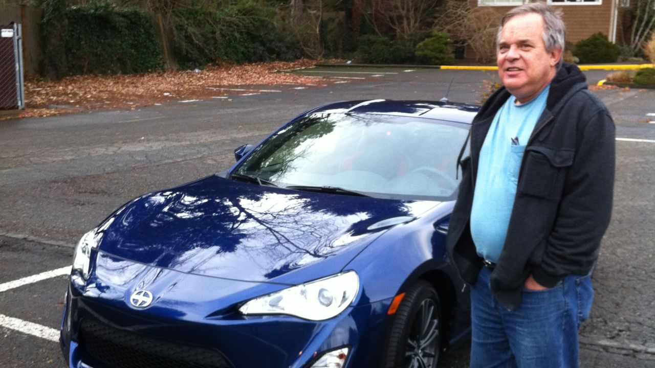 Alan Naiman poses next to one of his few splurges -- a Scion sports car. The thrifty social worker left more than $11 million to charities when he died in January.