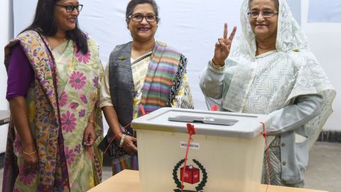 Bangladeshi Prime Minister Sheikh Hasina, right, flashes the victory symbol after casting her vote.