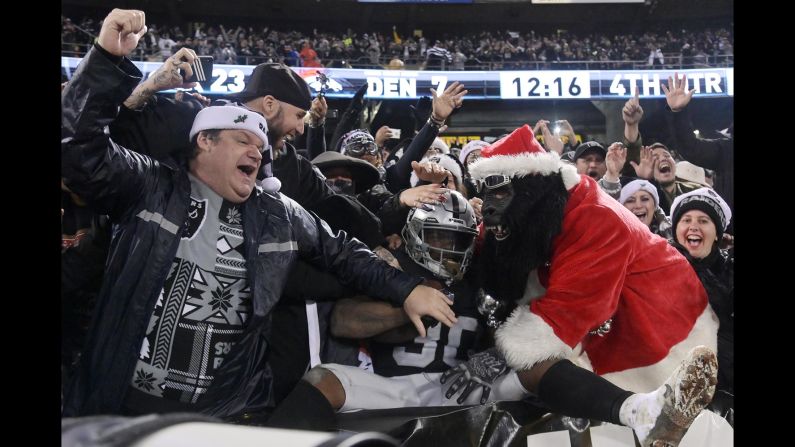 Oakland Raiders running back Jalen Richard, center, celebrates with fans after scoring a touchdown against the Denver Broncos in the fourth quarter on Monday, December 24, in Oakland, California. 